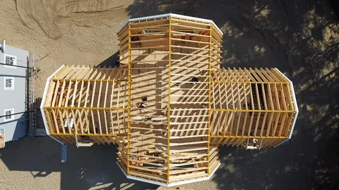 Aerial view of a cross-shaped house in framing