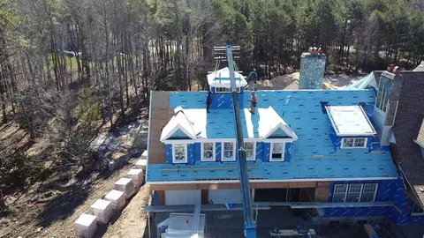 Crane setting a cupola on a roof with three dormers
