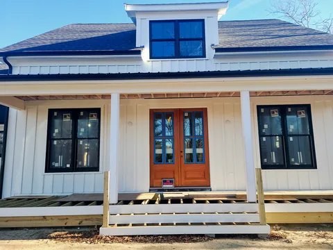 Board-and-batten farmhouse with wood double doors and a covered porch