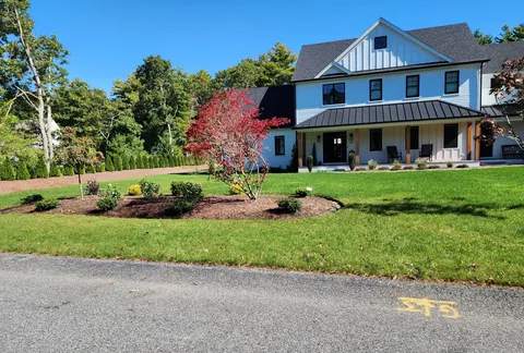 Finished modern farmhouse with a landscaped front yard and a red Japanese maple