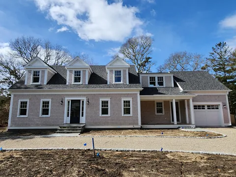 Gray shingle Cape with three dormers and an attached garage