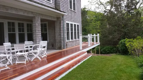 Mahogany deck with wide steps and white railings on a shingle home