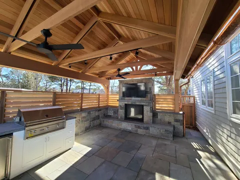 Cedar pavilion with an outdoor kitchen and a stone fireplace