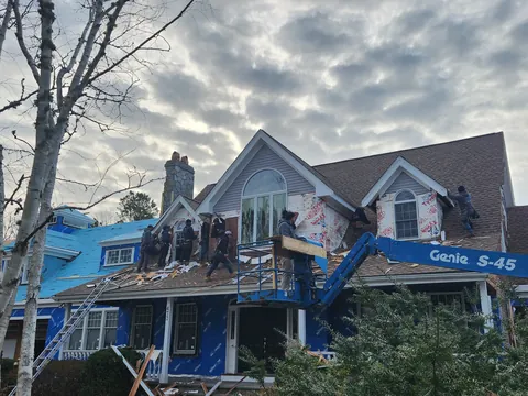 Crew building a roof addition from a lift