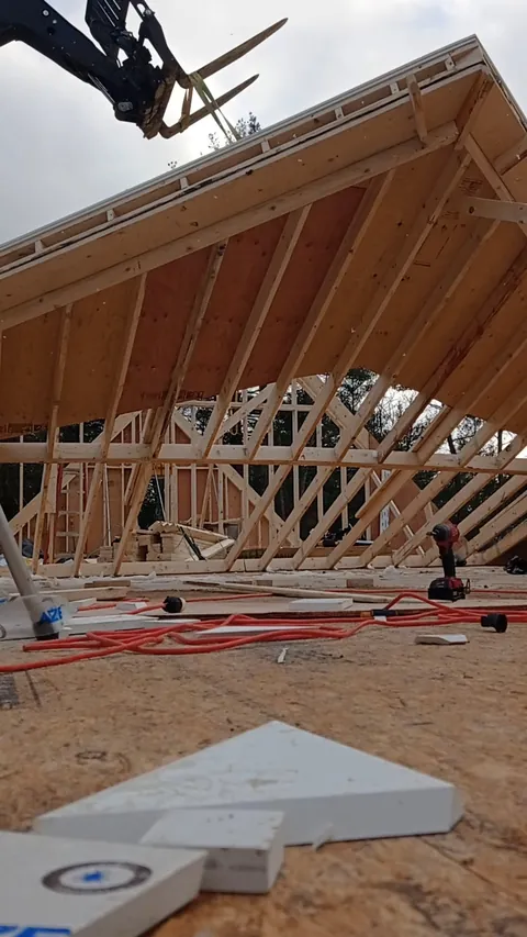 Roof trusses set in place with a telehandler on a new house