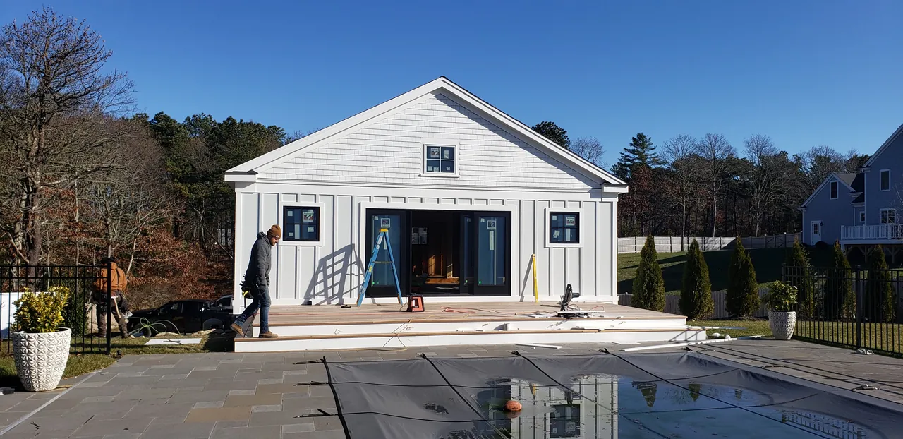 White modern farmhouse facing a pool terrace